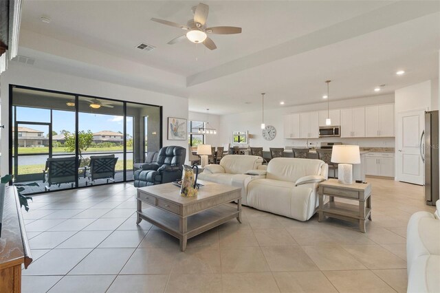 4961 Seafoam Trl, Bradenton, FL 34211 - living room featuring ceiling fan, recessed lighting, light tile patterned flooring, and a raised ceiling