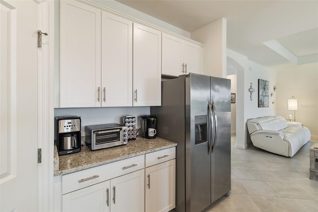 4961 Seafoam Trl, Bradenton, FL 34211 - kitchen featuring stainless steel fridge, arched walkways, open floor plan, light tile patterned flooring, and light stone counters