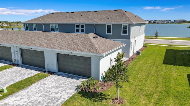 7352 Cabin Ln, Sarasota, FL 34240 - view of front of house featuring a water view, a front yard, roof with shingles, stucco siding, and a garage