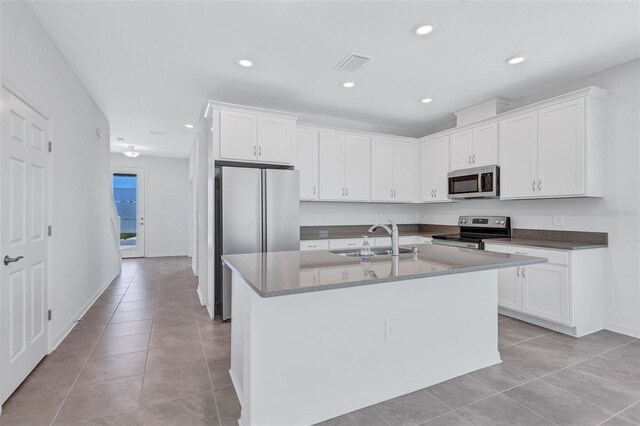 7352 Cabin Ln, Sarasota, FL 34240 - kitchen with stainless steel appliances, light tile patterned floors, white cabinets, a center island with sink, and recessed lighting