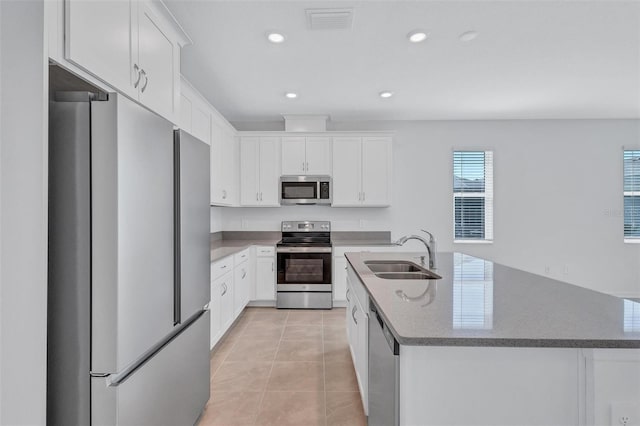 7352 Cabin Ln, Sarasota, FL 34240 - kitchen with appliances with stainless steel finishes, light tile patterned floors, white cabinetry, a center island with sink, and recessed lighting