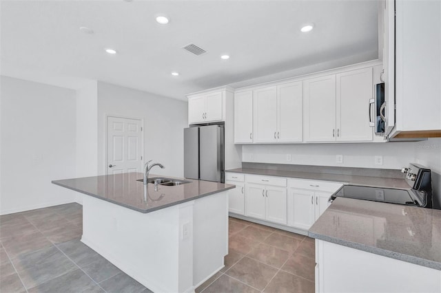 7352 Cabin Ln, Sarasota, FL 34240 - kitchen with appliances with stainless steel finishes, white cabinets, dark stone counters, recessed lighting, and a kitchen island with sink