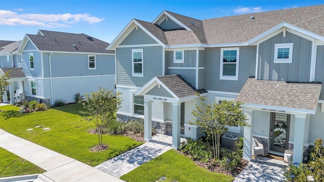 7352 Cabin Ln, Sarasota, FL 34240 - view of front of house with board and batten siding, a front yard, and a shingled roof