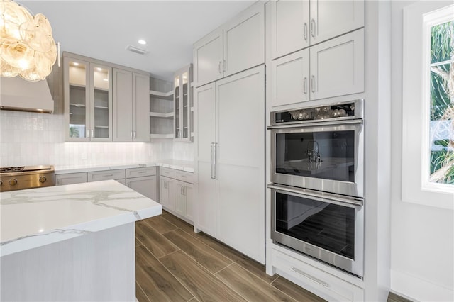 646 Calle Del Otono, Sarasota, FL 34242 - kitchen with stainless steel double oven, light stone counters, paneled built in refrigerator, decorative backsplash, and dark wood-style floors