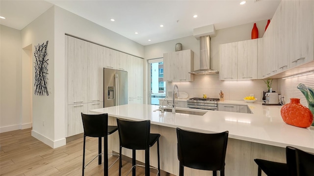 626 Rawls Ave Unit 626, Sarasota, FL 34236 - kitchen featuring appliances with stainless steel finishes, wall chimney exhaust hood, a peninsula, light wood finished floors, and light countertops