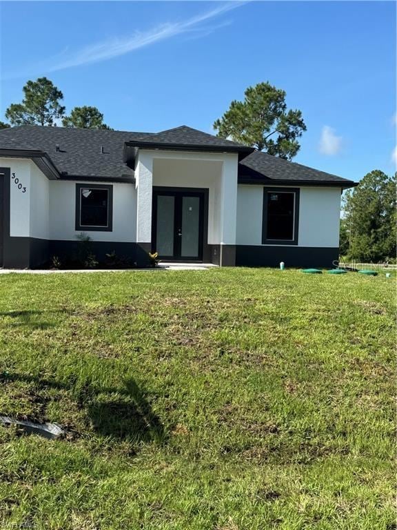 3003 18th St W, Lehigh Acres, FL 33971 - view of front facade with stucco siding, a front yard, and french doors
