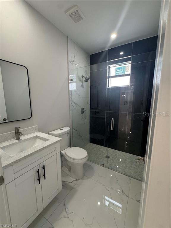 3003 18th St W, Lehigh Acres, FL 33971 - full bathroom featuring vanity, a marble finish shower, and marble finish floors