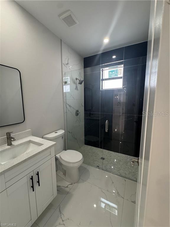 3003 18th St W, Lehigh Acres, FL 33971 - full bathroom featuring vanity, a marble finish shower, and marble finish flooring