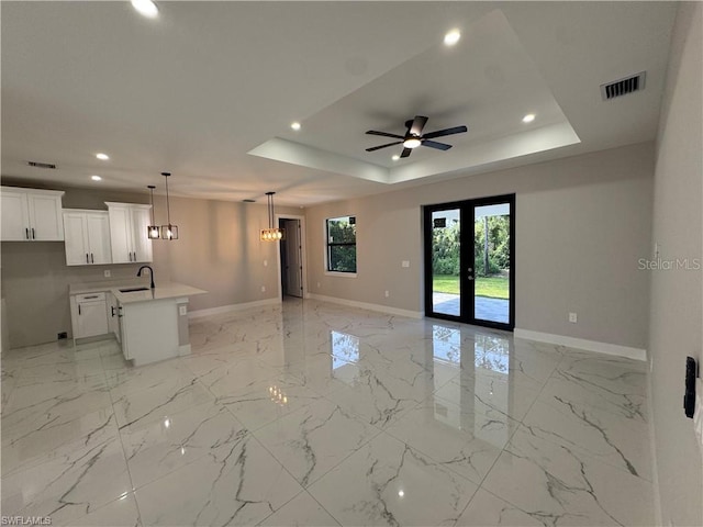 3003 18th St W, Lehigh Acres, FL 33971 - unfurnished living room with recessed lighting, a ceiling fan, a tray ceiling, light marble finish floors, and a chandelier