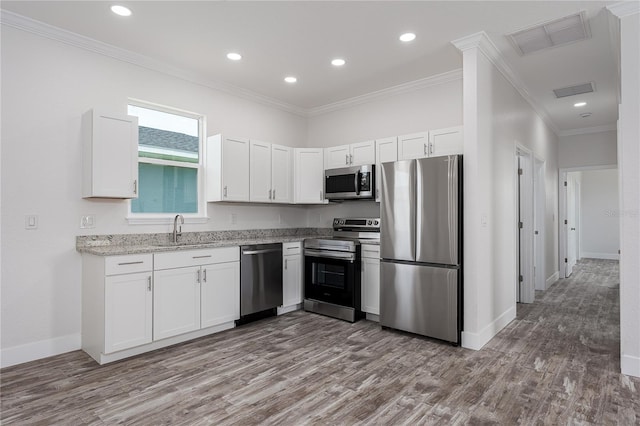 1515 2nd Ave W, Palmetto, FL 34221 - kitchen with appliances with stainless steel finishes, ornamental molding, white cabinets, wood finished floors, and light stone countertops
