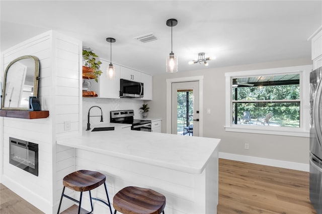 4041 Linwood St, Sarasota, FL 34232 - kitchen featuring appliances with stainless steel finishes, light countertops, white cabinetry, and light wood-style flooring