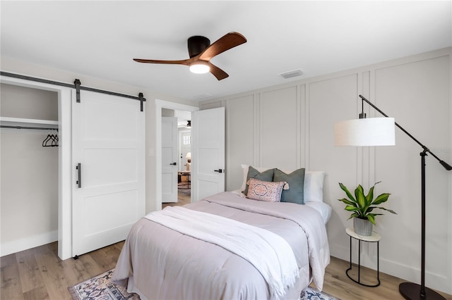 4041 Linwood St, Sarasota, FL 34232 - bedroom with a decorative wall, a barn door, light wood-style flooring, a closet, and a ceiling fan