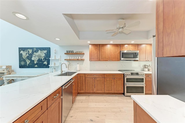 6111 Courtside Dr Unit 61, Bradenton, FL 34210 - kitchen featuring appliances with stainless steel finishes, open shelves, light wood-style flooring, a ceiling fan, and brown cabinetry