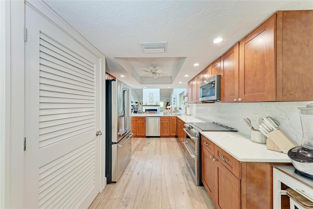 6111 Courtside Dr Unit 61, Bradenton, FL 34210 - kitchen featuring appliances with stainless steel finishes, a raised ceiling, brown cabinetry, light countertops, and ceiling fan