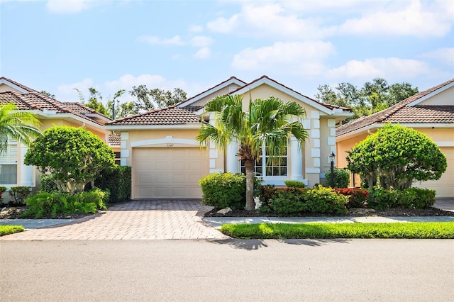 7747 33rd St E, Sarasota, FL 34243 - view of front of property with an attached garage, a tiled roof, driveway, and stucco siding