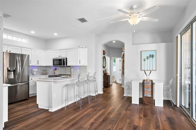 7747 33rd St E, Sarasota, FL 34243 - kitchen featuring stainless steel appliances, arched walkways, light countertops, dark wood finished floors, and recessed lighting