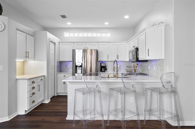 7747 33rd St E, Sarasota, FL 34243 - kitchen with appliances with stainless steel finishes, a peninsula, light countertops, white cabinetry, and dark wood-style floors
