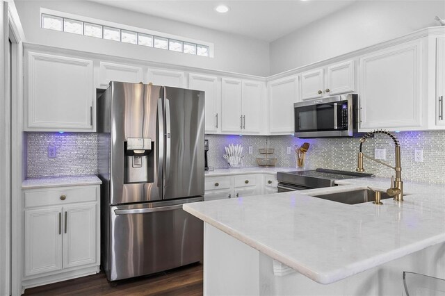 7747 33rd St E, Sarasota, FL 34243 - kitchen with appliances with stainless steel finishes, a peninsula, white cabinetry, and recessed lighting