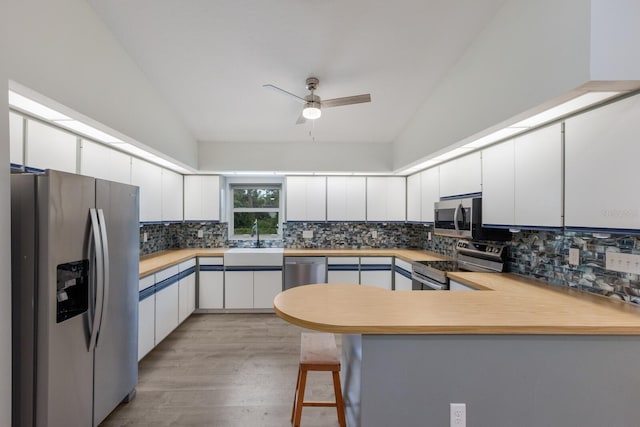 8985 Pohoy Ave, Sarasota, FL 34231 - kitchen with appliances with stainless steel finishes, a peninsula, backsplash, and vaulted ceiling