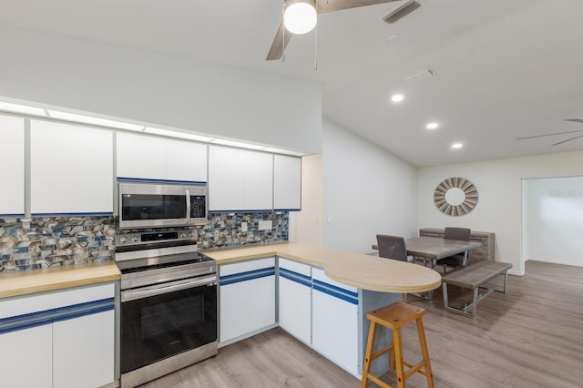 8985 Pohoy Ave, Sarasota, FL 34231 - kitchen with stainless steel appliances, ceiling fan, a peninsula, tasteful backsplash, and lofted ceiling