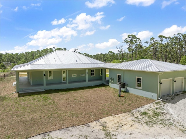 8146 Tropicaire Blvd, North Port, FL 34291 - back of property featuring a garage, covered porch, a metal roof, and gravel driveway
