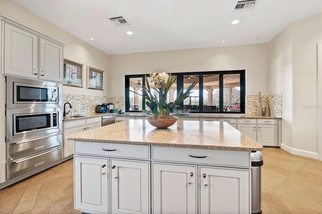 11221 Sandhill Preserve Dr, Sarasota, FL 34238 - kitchen featuring backsplash, a center island, light stone countertops, light tile patterned floors, and recessed lighting