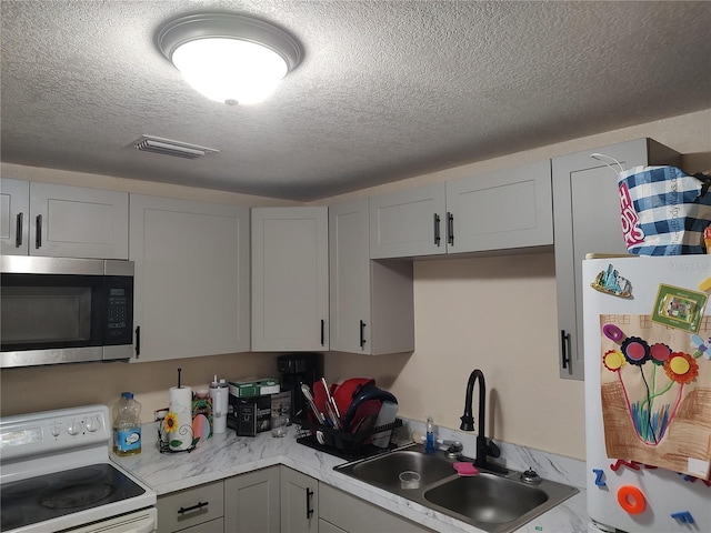 1423 17th Ave E, Bradenton, FL 34208 - kitchen featuring white range with electric cooktop, stainless steel microwave, fridge, a textured ceiling, and gray cabinets