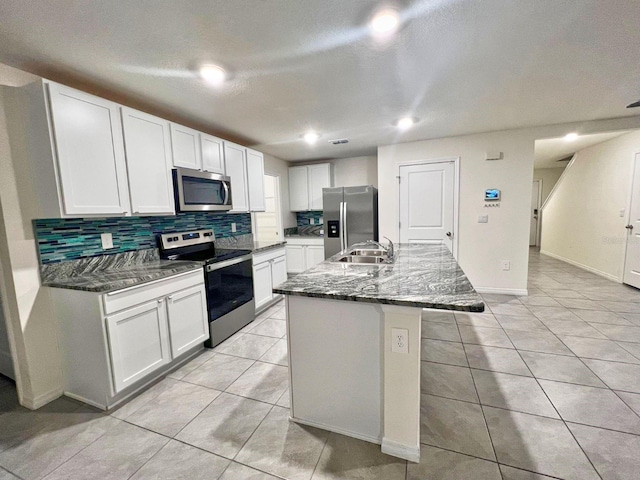 2824 Rock Sound St, Bradenton, FL 34208 - kitchen with appliances with stainless steel finishes, backsplash, a kitchen island with sink, white cabinets, and light tile patterned floors
