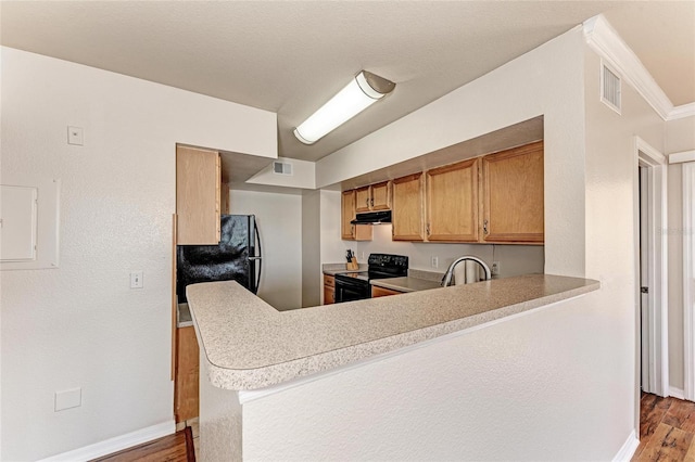1030 Villagio Cir Unit 103, Sarasota, FL 34237 - kitchen featuring black appliances, under cabinet range hood, wood finished floors, a peninsula, and light countertops