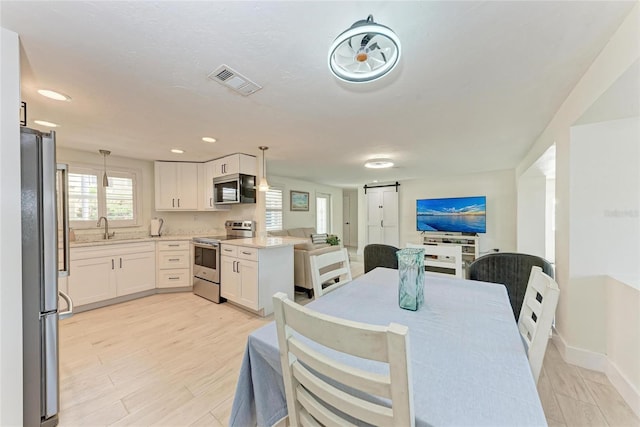 726 Jungle Queen Way, Longboat Key, FL 34228 - dining space with a barn door, light wood-style flooring, and recessed lighting