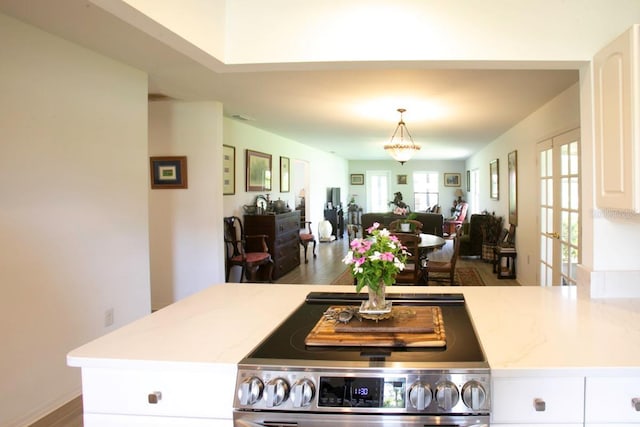 6504 Heritage Ln Unit 99, Bradenton, FL 34209 - kitchen with electric stove, open floor plan, white cabinets, decorative light fixtures, and wood finished floors