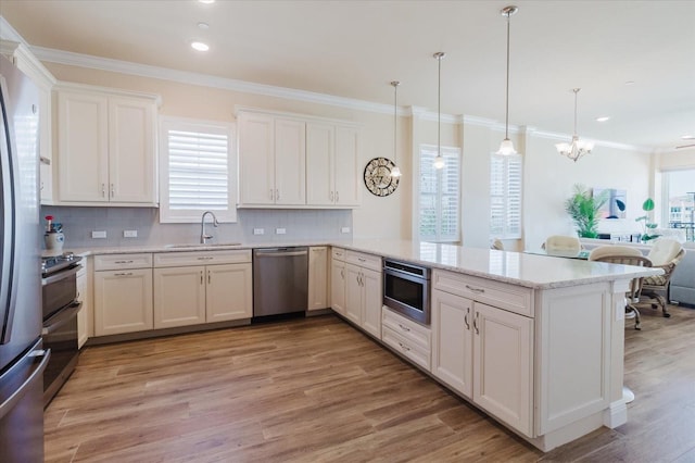 501 Tamiami Trl N Unit 201, Venice, FL 34285 - kitchen featuring appliances with stainless steel finishes, a peninsula, light wood-style flooring, crown molding, and backsplash