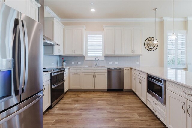 501 Tamiami Trl N Unit 201, Venice, FL 34285 - kitchen with stainless steel appliances, crown molding, light wood finished floors, backsplash, and white cabinets