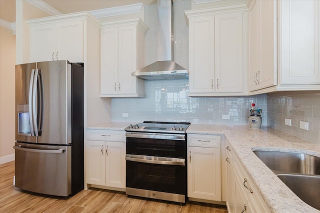 501 Tamiami Trl N Unit 201, Venice, FL 34285 - kitchen featuring appliances with stainless steel finishes, wall chimney exhaust hood, light wood finished floors, tasteful backsplash, and white cabinetry