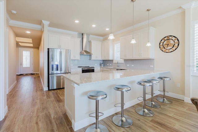 501 Tamiami Trl N Unit 201, Venice, FL 34285 - kitchen with stainless steel appliances, wall chimney range hood, a peninsula, light wood-style flooring, and backsplash