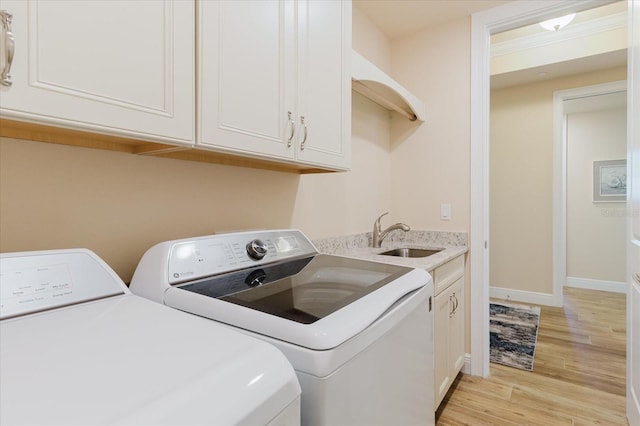 501 Tamiami Trl N Unit 201, Venice, FL 34285 - washroom featuring independent washer and dryer, light wood-style flooring, and cabinet space