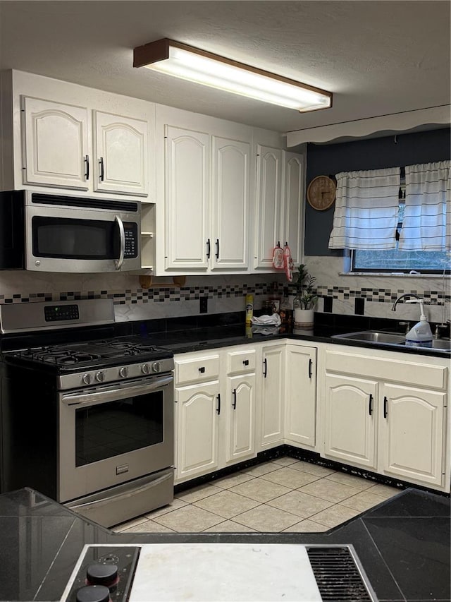 1123 NW 192nd Ave, Gainesville, FL 32609 - kitchen featuring stainless steel appliances, light tile patterned floors, dark countertops, backsplash, and white cabinetry