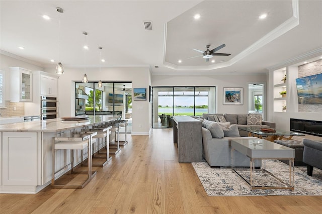 3968 Santa Caterina Blvd, Bradenton, FL 34211 - living room with a ceiling fan, light wood-style flooring, recessed lighting, ornamental molding, and a raised ceiling
