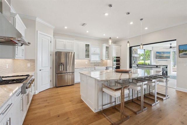 3968 Santa Caterina Blvd, Bradenton, FL 34211 - kitchen featuring stainless steel appliances, wall chimney exhaust hood, plenty of natural light, a spacious island, and crown molding