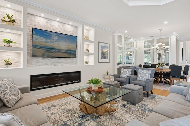 3968 Santa Caterina Blvd, Bradenton, FL 34211 - living room featuring ornamental molding, a chandelier, wood finished floors, a glass covered fireplace, and recessed lighting
