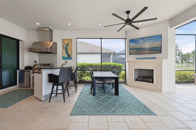 3968 Santa Caterina Blvd, Bradenton, FL 34211 - kitchen featuring wall chimney exhaust hood, a ceiling fan, stainless steel fridge, a kitchen bar, and recessed lighting