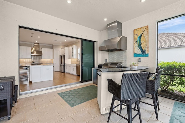 3968 Santa Caterina Blvd, Bradenton, FL 34211 - kitchen with wall chimney range hood, freestanding refrigerator, tasteful backsplash, white cabinets, and recessed lighting