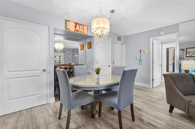 6310 Midnight Pass Rd Unit 405N, Sarasota, FL 34242 - dining room with a chandelier, light wood finished floors, and a textured ceiling