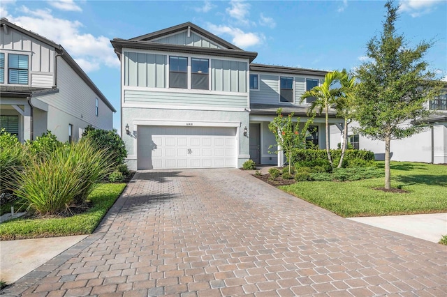16418 Slate Pl, Lakewood Ranch, FL 34211 - view of front of property with board and batten siding, an attached garage, decorative driveway, stucco siding, and a front yard