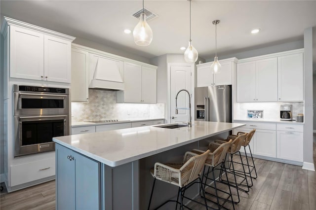 16418 Slate Pl, Lakewood Ranch, FL 34211 - kitchen with appliances with stainless steel finishes, custom exhaust hood, light wood-style floors, tasteful backsplash, and recessed lighting