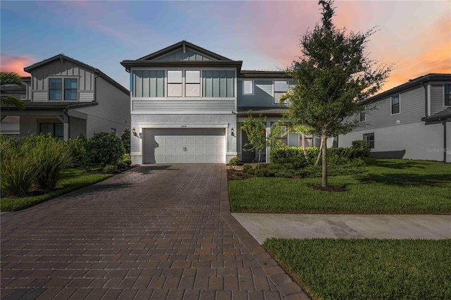16418 Slate Pl, Lakewood Ranch, FL 34211 - view of front of house featuring decorative driveway, an attached garage, a lawn, board and batten siding, and stucco siding