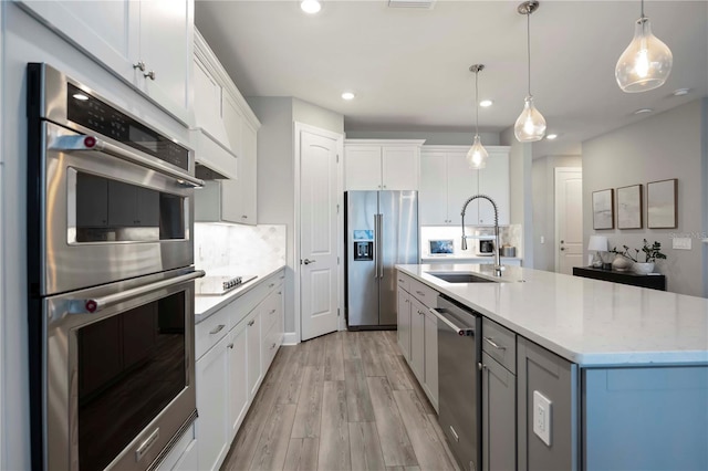 16418 Slate Pl, Lakewood Ranch, FL 34211 - kitchen with appliances with stainless steel finishes, light wood-type flooring, recessed lighting, white cabinets, and pendant lighting