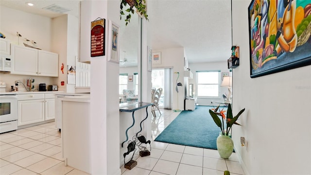 5078 47th St W, Bradenton, FL 34210 - kitchen featuring white appliances, light tile patterned floors, white cabinetry, a textured ceiling, and light countertops