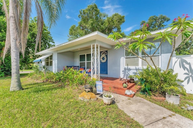 401 N Jefferson Ave, Sarasota, FL 34237 - view of front of house with stucco siding, a porch, and a front lawn