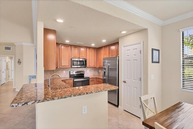 6512 Grand Estuary Trl Unit 101, Bradenton, FL 34212 - kitchen with stainless steel appliances, light tile patterned floors, light stone counters, a peninsula, and backsplash